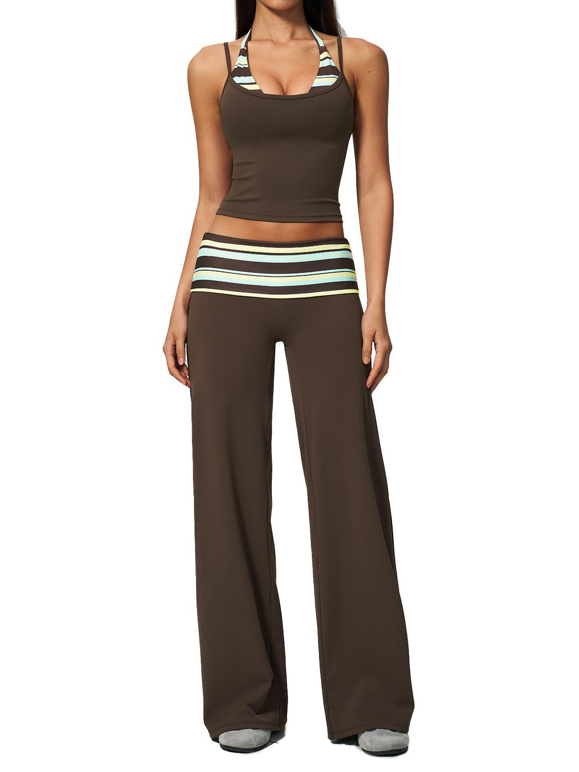 Model in a brown cropped camisole and wide leg pants with a striped fold over waistband on a gray studio background