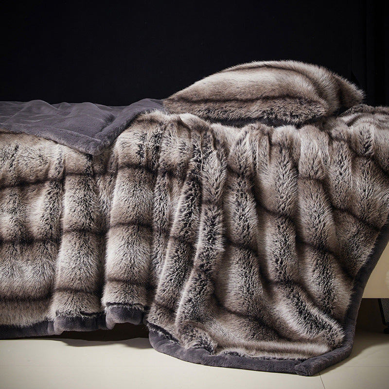 Taupe Gray option: silver gray vegan fur blanket with dark tipped pile and a gray border draped over a bed