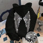 Black hoodie back with sparkling rhinestone wings on a chair, with a stone close-up
