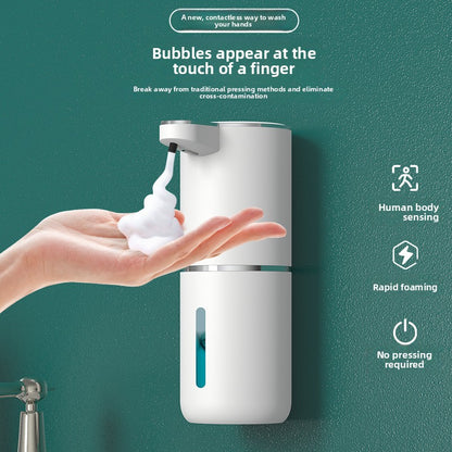 White ABS automatic foaming soap dispenser with foam in an open hand on a teal wall