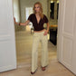 Model in a brown top and beige cuffed wide leg trousers standing in a doorway