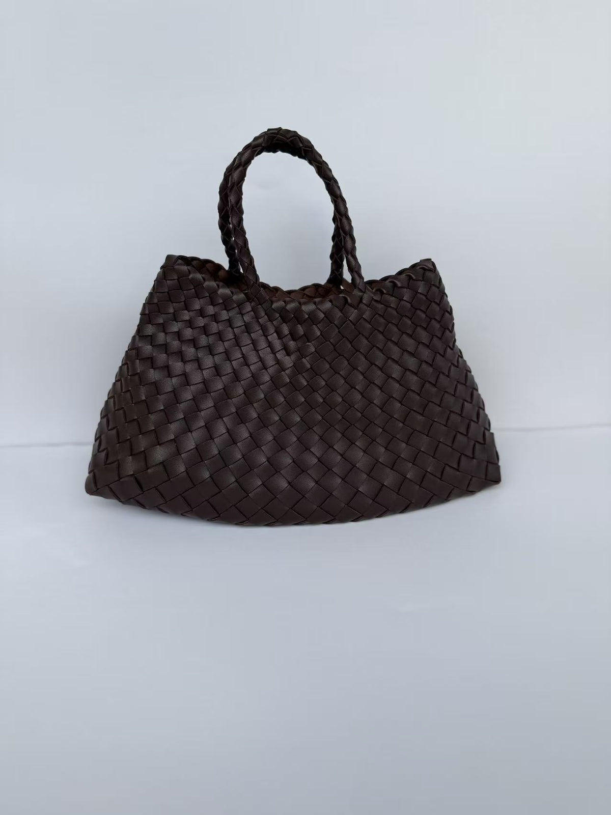 Dark brown woven PU handbag, front view with two braided top handles on a pale backdrop