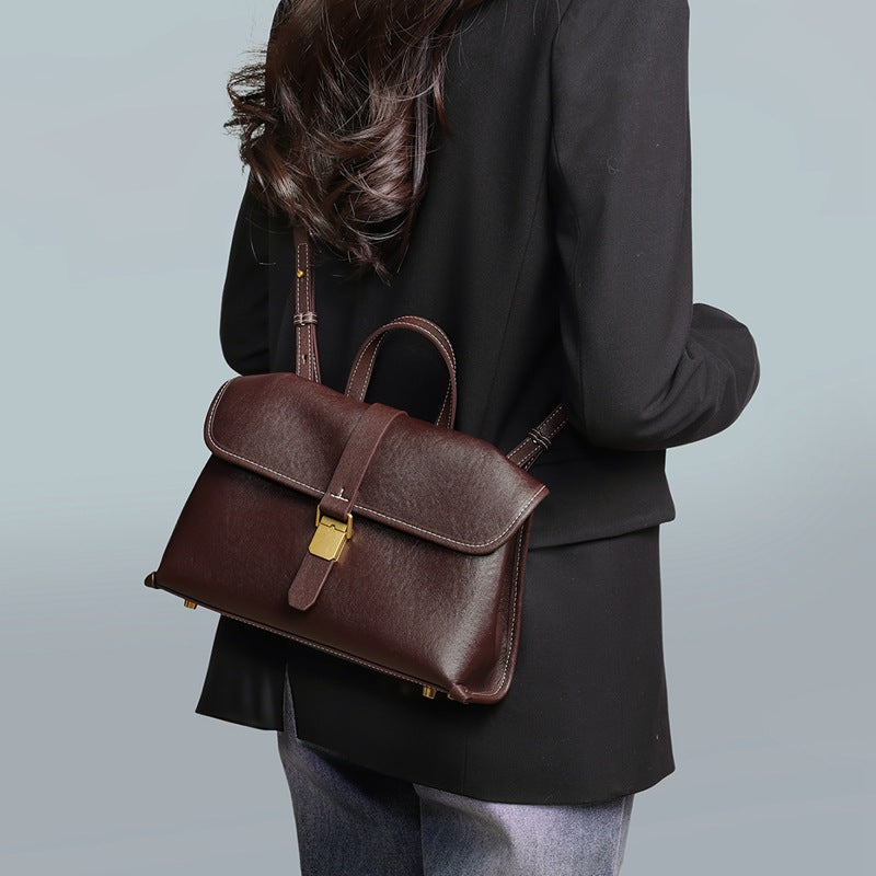 Woman seen from behind wearing the coffee brown flap satchel across the body over a black blazer