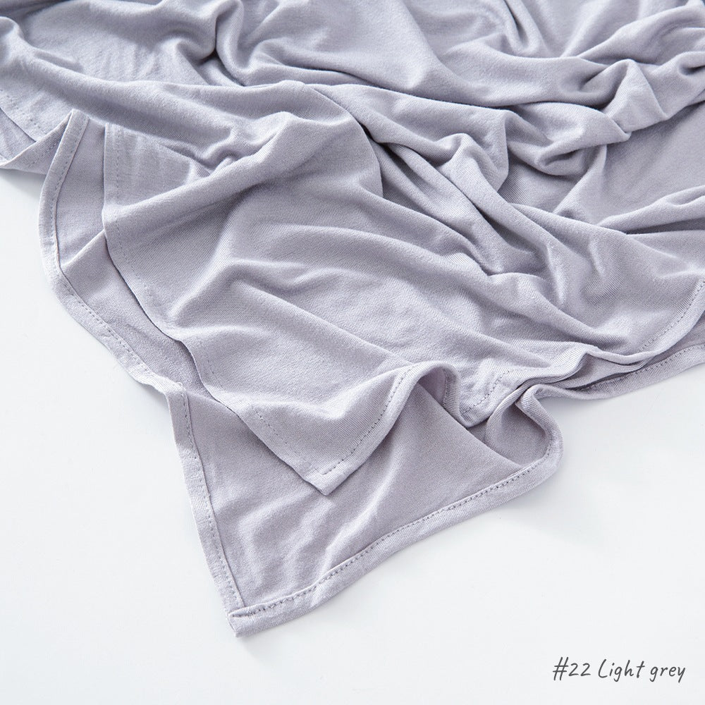 Corner of the modal cotton headscarf wrap showing the neat rolled hem and flat solid color