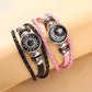 Pink and black braided cord bracelets worn together on a wrist with sun and moon charms