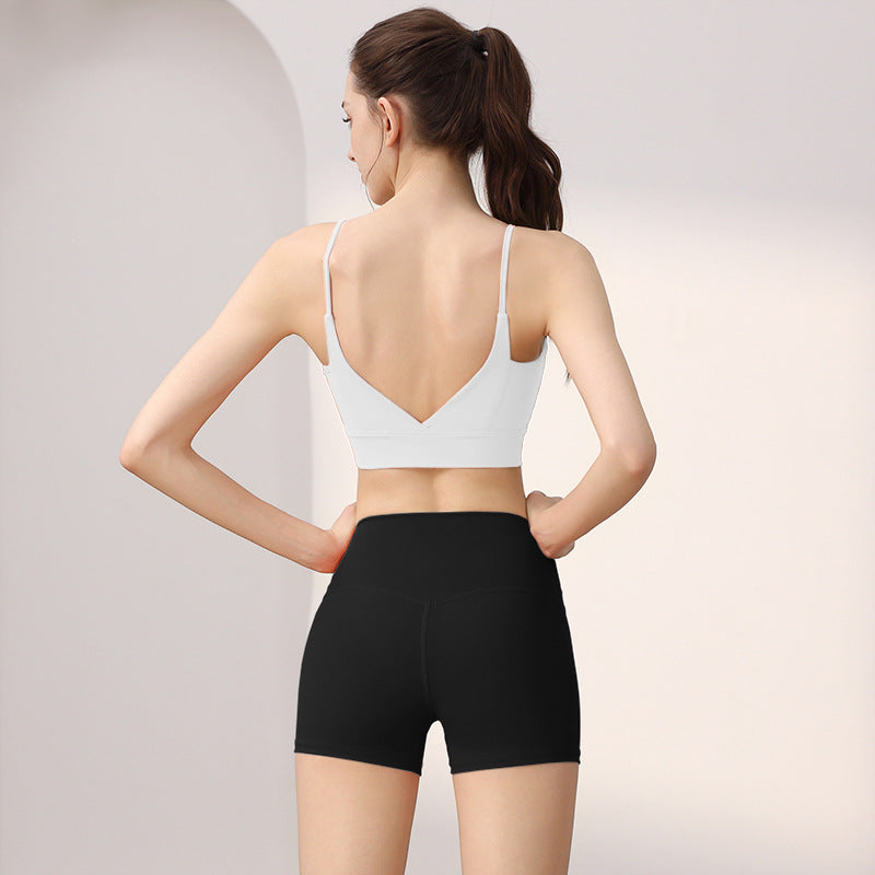 Back view of a woman in a white V-back sports bra and black high-waist shorts set, size L option