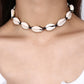 Close view of the cowrie shell choker worn on black cord above a white ribbed top
