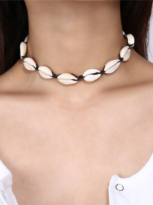 Close view of the cowrie shell choker worn on black cord above a white ribbed top