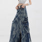 Model resting a hand in the high-waist pocket of the marbled denim maxi skirt with exposed front zippers