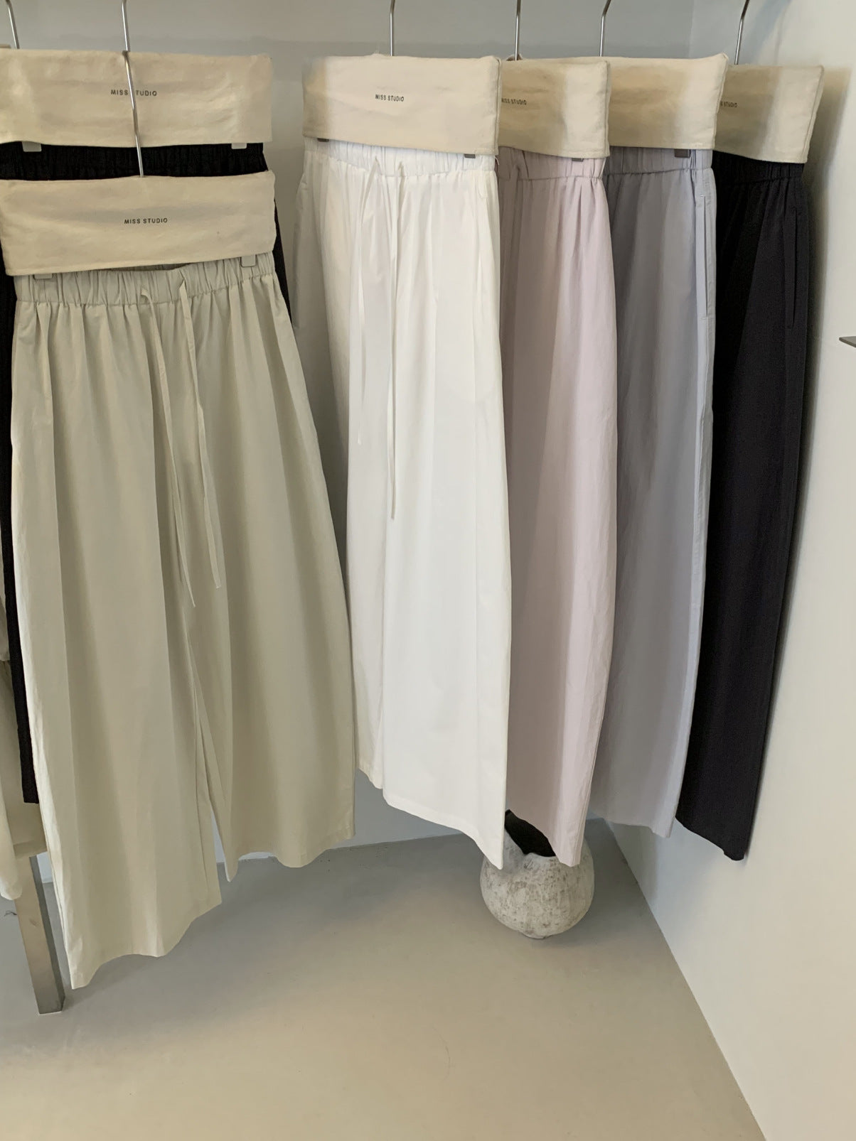 Cotton wide leg trousers on hangers in white, light pink, lilac and carbon ash tones
