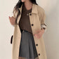Light khaki single breasted long trench coat buttoned partway with rolled sleeves