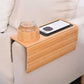 Bamboo armrest tray on a sofa arm with a glass of water in a bamboo cup holder and a phone on a black pad