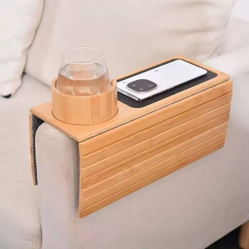 Bamboo armrest tray on a sofa arm with a glass of water in a bamboo cup holder and a phone on a black pad