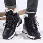 Pair of black winter boots in snow showing the deep zigzag lugs of the outsole