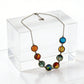 Solar system cabochon necklace draped over a clear acrylic block, lobster clasp and extender chain visible