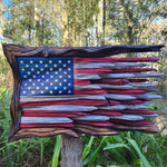 Rustic wooden American flag wall art displayed outdoors on a garden post