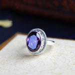 Statement ring front view with a large oval faceted purple stone in a silver-tone bezel