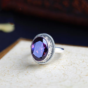 Statement ring front view with a large oval faceted purple stone in a silver-tone bezel