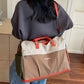 Beige and orange colorblock travel duffel worn on the back with an orange crossbody strap
