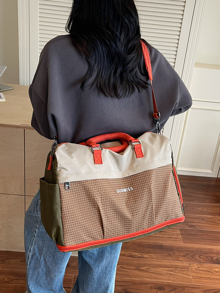 Beige and orange colorblock travel duffel worn on the back with an orange crossbody strap