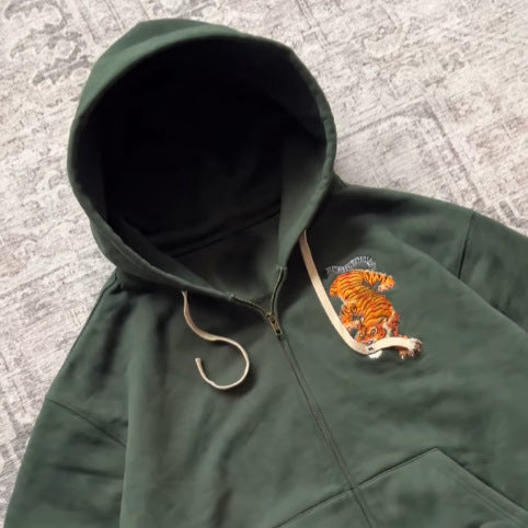 Close-up of the hood, zipper and orange tiger embroidery on the dark green zip hooded sweatshirt
