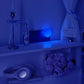 Blue heart night light glowing next to a wall socket in a dark room