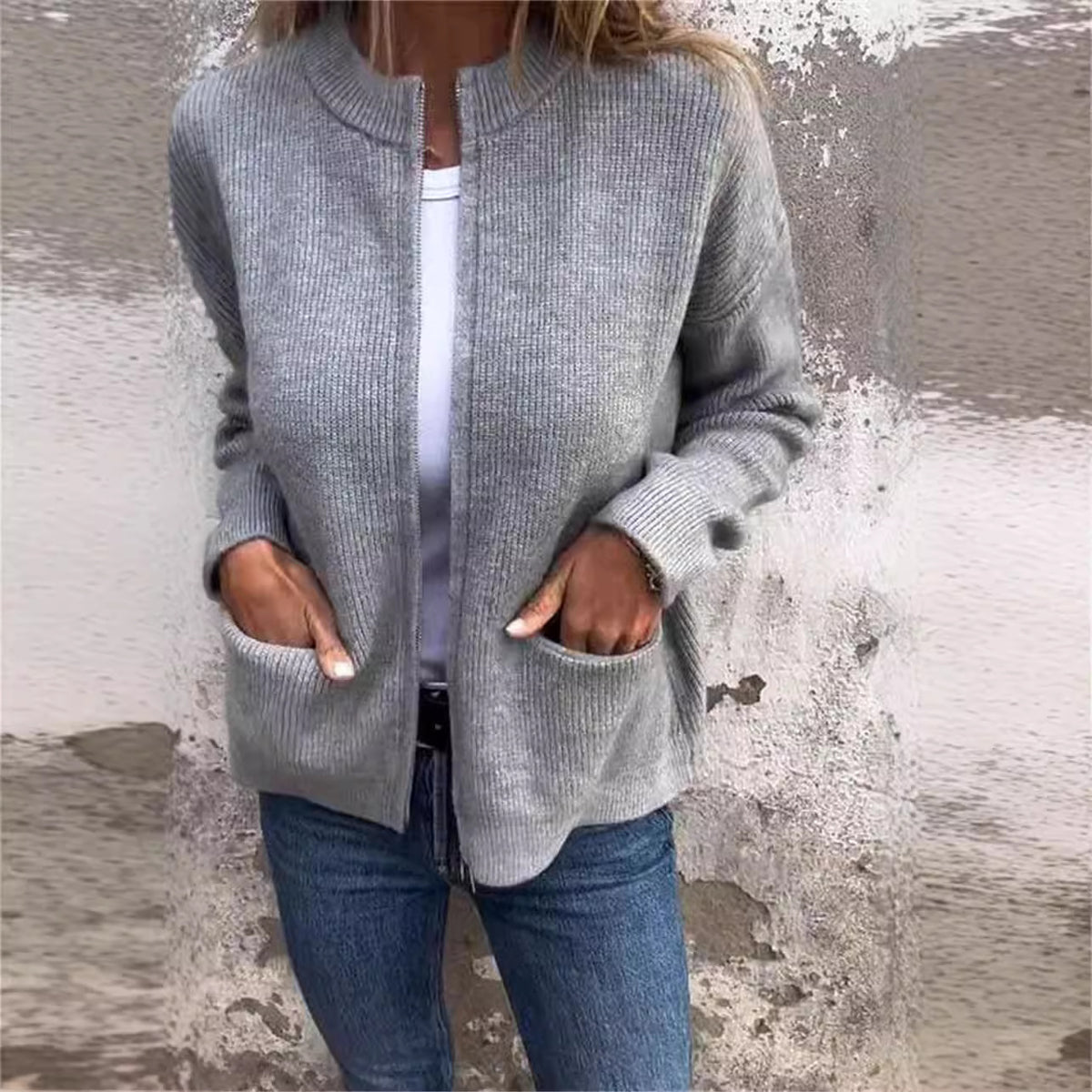 Gray zip-front cardigan with round neck and two patch pockets, worn over a white top and jeans