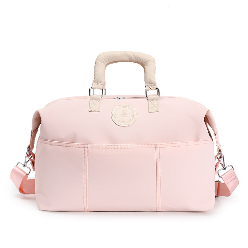 Pink duffel travel bag with cream padded handles, front slip pockets and shoulder strap, second view