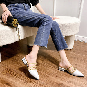 Black and beige pointed-toe mules with gold-tone studded straps