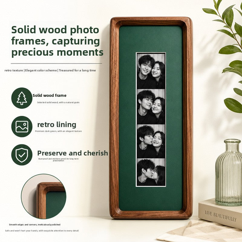 Solid walnut photo strip frame with dark green lining holding four black and white photos beside a glass vase