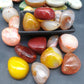 Smooth violet banded agate tumbled stones on a grey studio surface