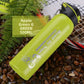 Apple green stainless steel sports bottle with black flip lid lying on coffee beans and fern leaves, green option