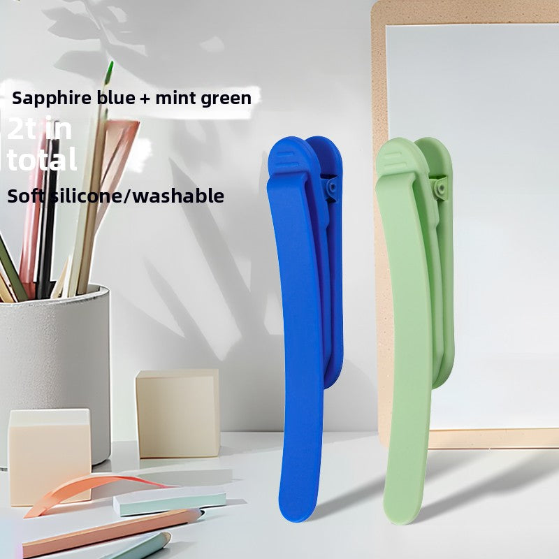 Two piece set of silicone bookmark clips in sapphire blue and mint green on a desk