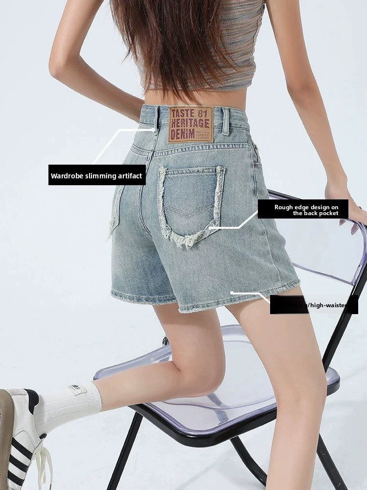Rear angle of mid-thigh denim shorts showing frayed raw-edge back patch pockets
