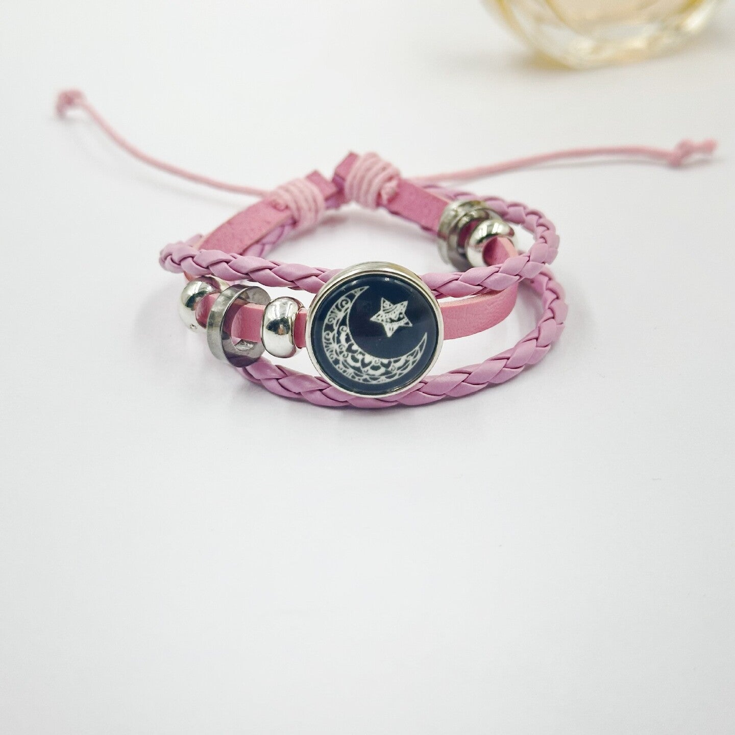 Pink and black cord bracelets laid out to show the matching sun and moon charms