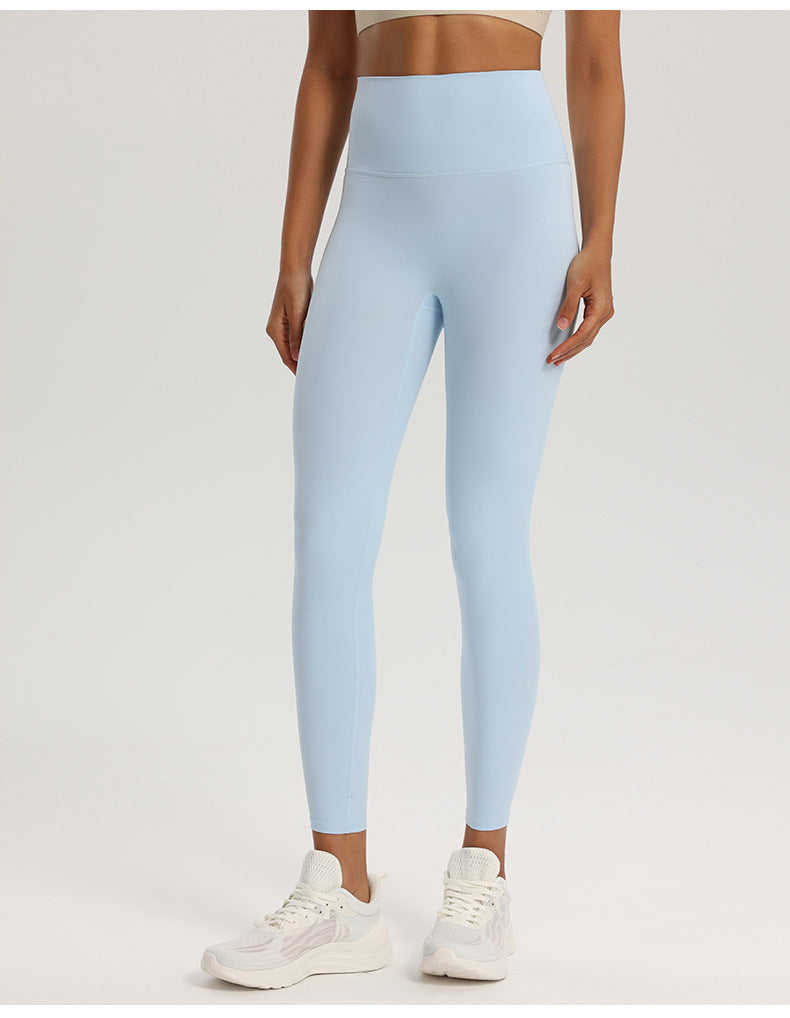 Wide high-rise waistband yoga leggings, nylon spandex knit, worn against a studio wall