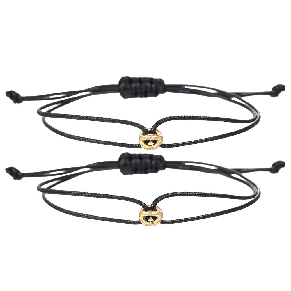 Two black cord friendship bracelets with gold tone charms and adjustable slide knots