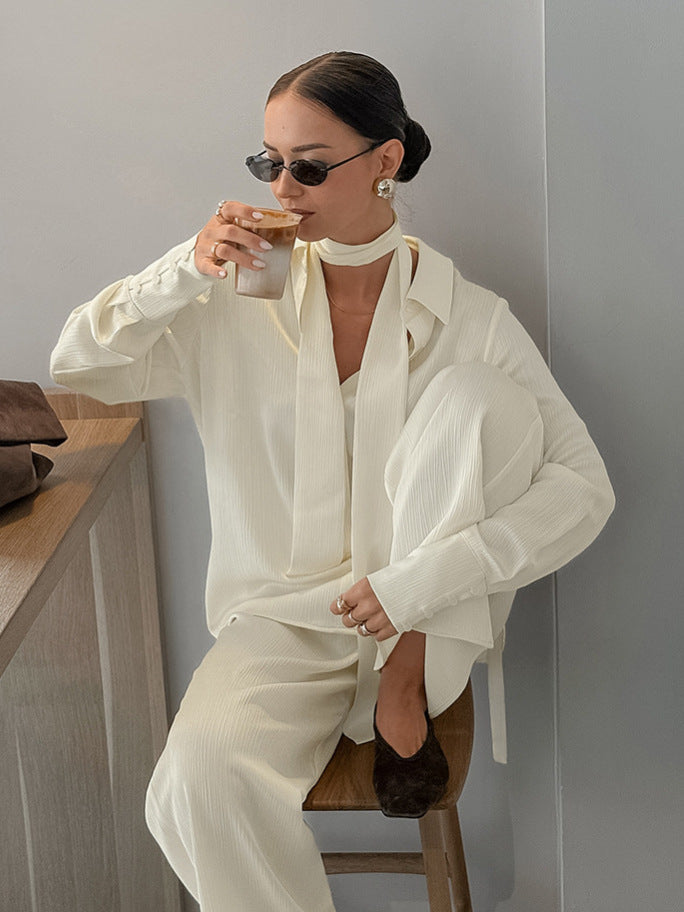 Buttercream loose shirt worn open over the wide leg trousers set, standing with a coffee in hand