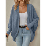Woman wearing a blue open front knit cardigan over a white top and jeans