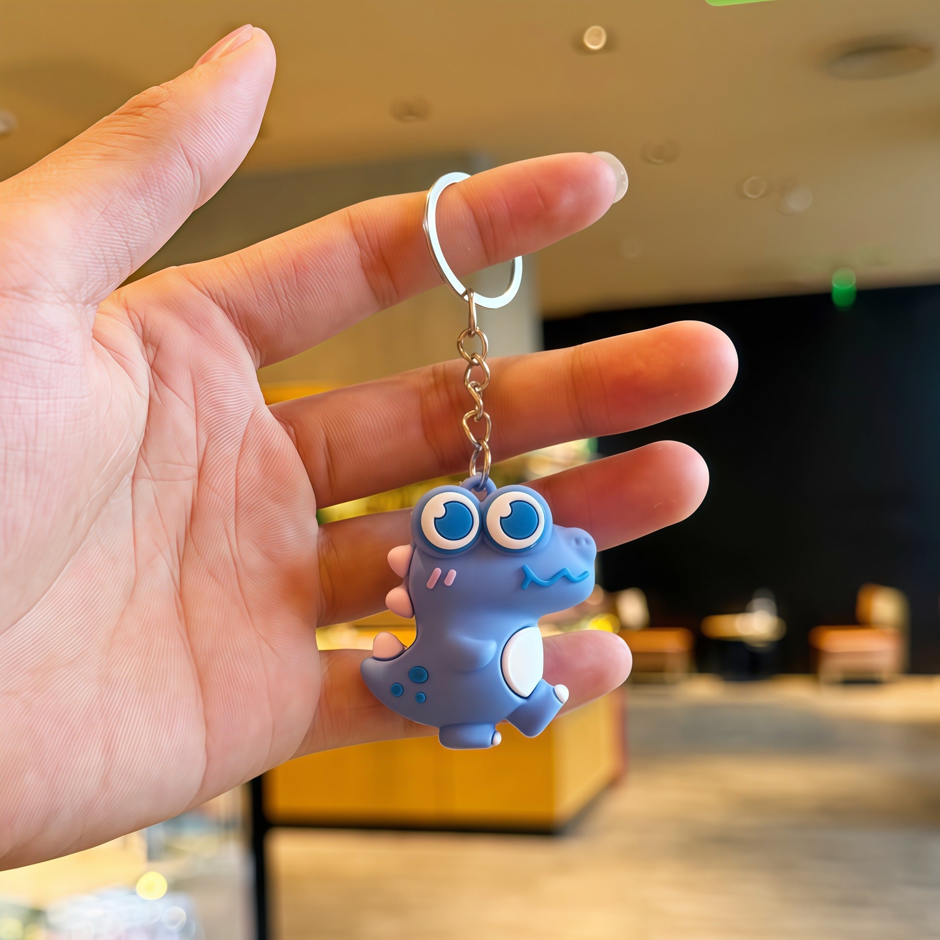 Top down view of the cartoon dinosaur keychain charm and its ring