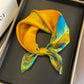 Yellow and teal abstract printed square scarf with a satin sheen and hemmed edges, shown displayed