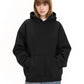 A woman in a black pullover hoodie with jeans, hands in the front pouch pocket, on a white background