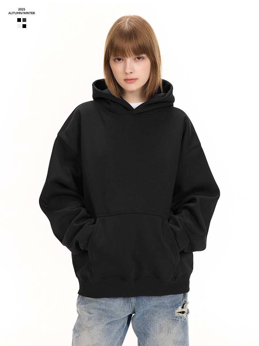 A woman in a black pullover hoodie with jeans, hands in the front pouch pocket, on a white background