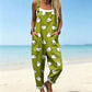 Woman in olive green overalls with a white bird print, cuffed legs and hip pockets on a beach