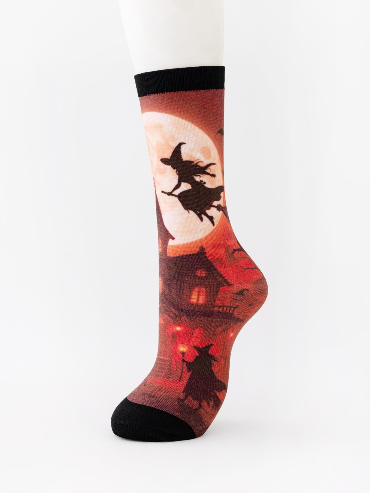 Mid-calf sock on a mannequin printed with a red moon, a witch on a broom and a haunted house