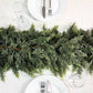 Top down view of the cedar garland as a table runner between two white place settings and wine glasses