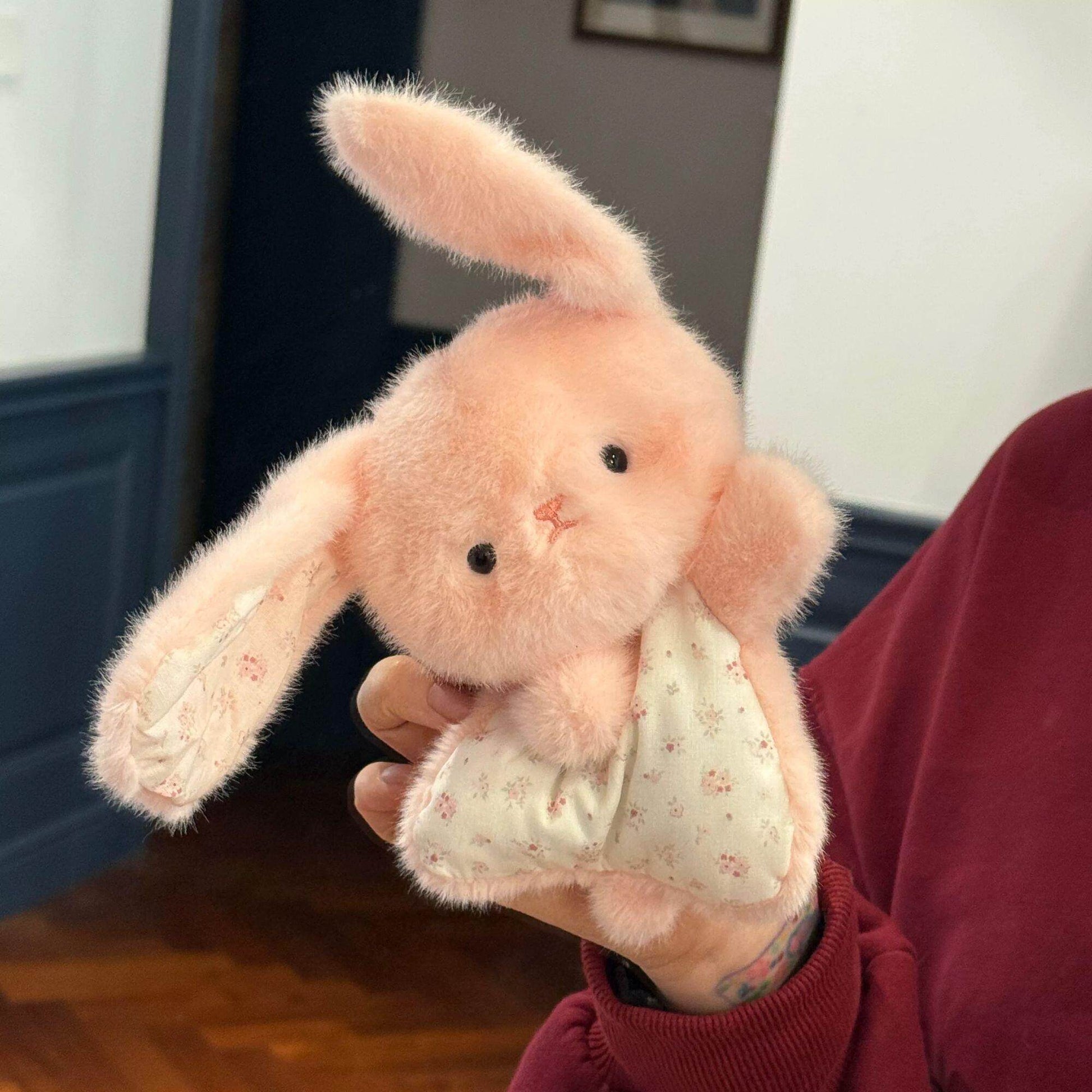 Pink plush bunny squishy bean bag toy held up, floppy ears and small black bead eyes