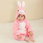 Baby in a pink rabbit flannel romper with a hood and long ears, sitting on a cream rug