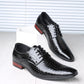 Pair of black croc embossed derby shoes with pointed toes and red-brown heels on a white block