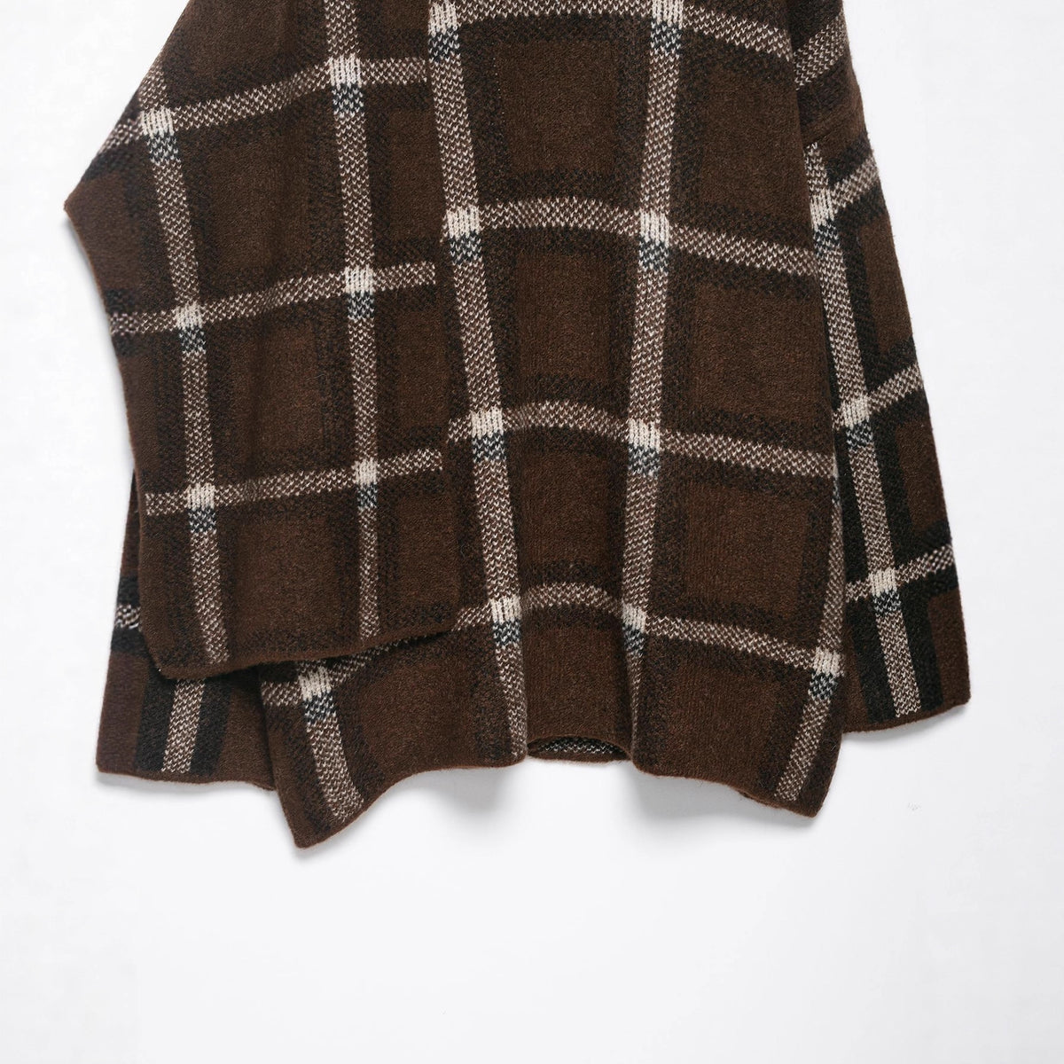 Close-up of the brown plaid knit side panel and sleeve edge of the cardigan on a white background